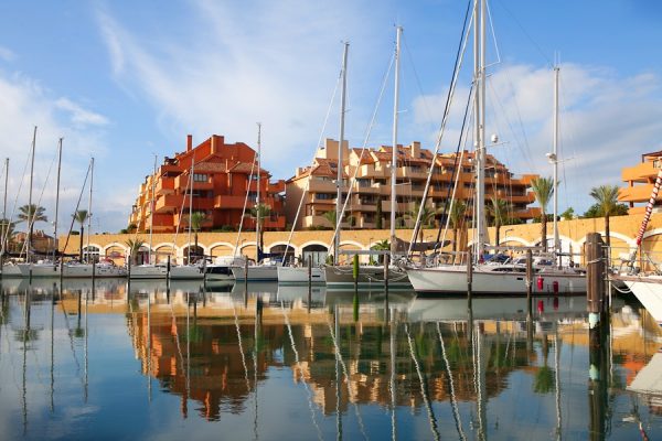 Sailboats moored directly beneath terracotta apartments